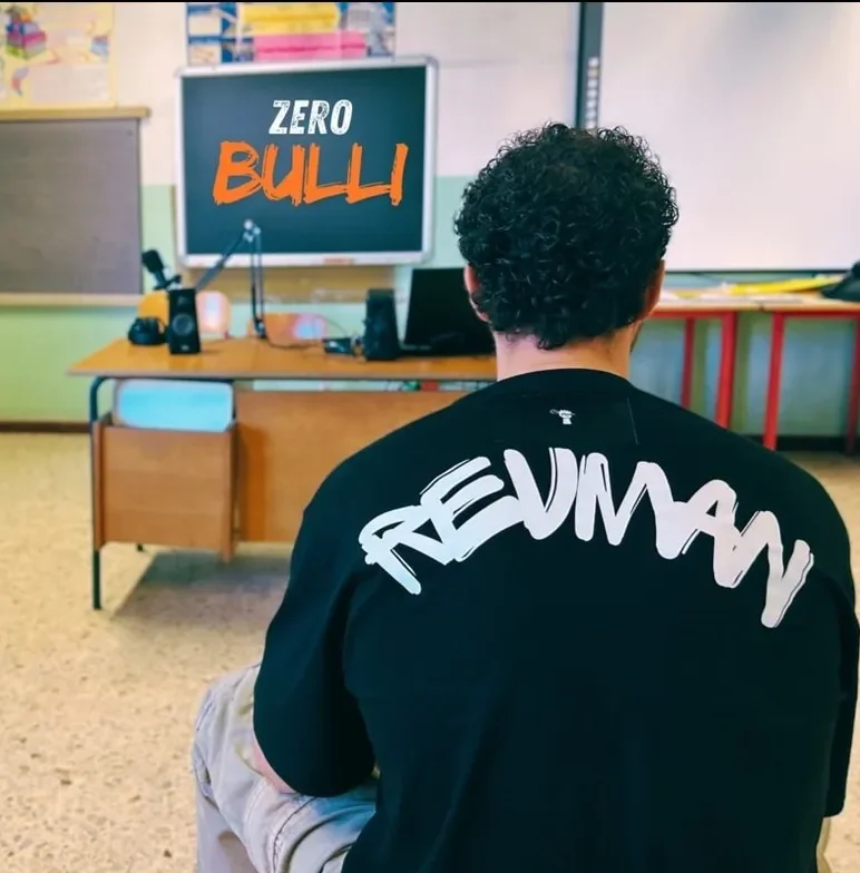 Revman, il poliziotto rapper, di spalle in un’aula scolastica durante un incontro del progetto Zero Bulli